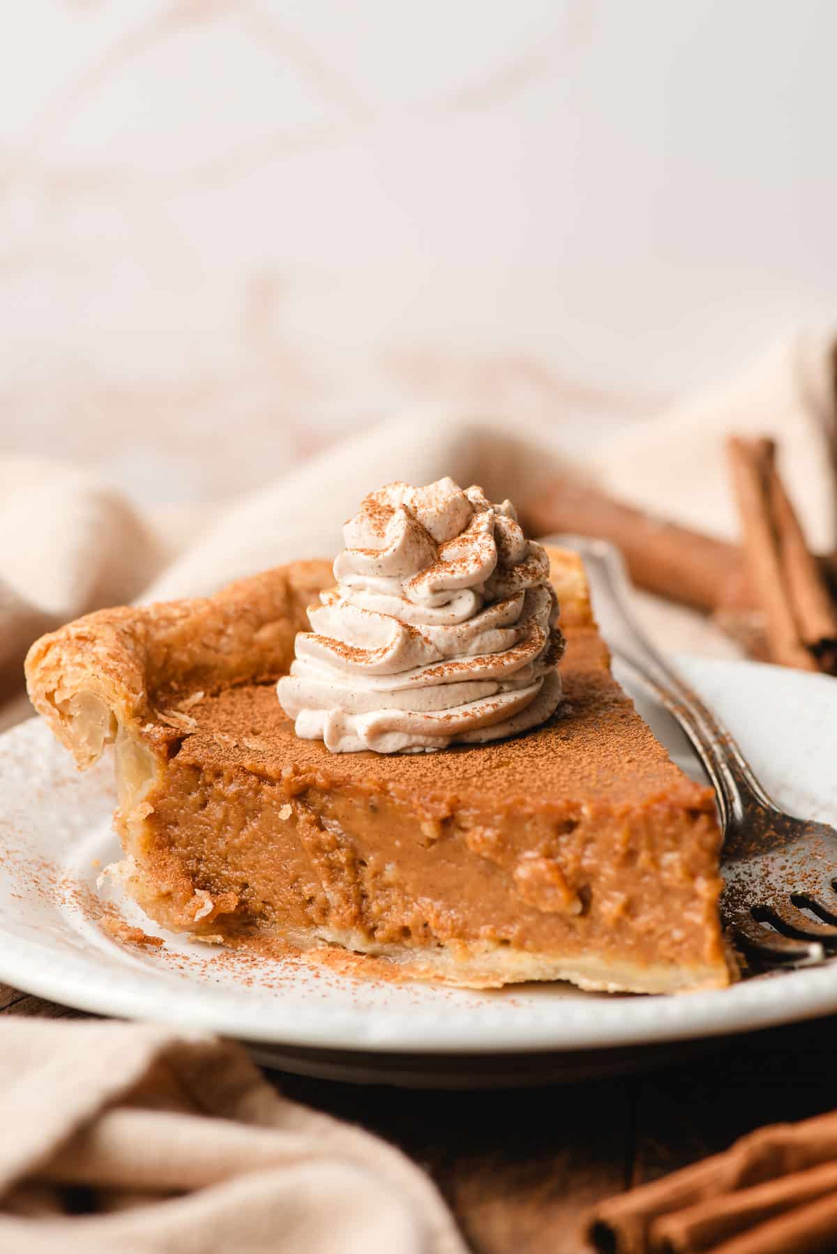 Slice of pumpkin pie topped with cinnamon whipped cream.