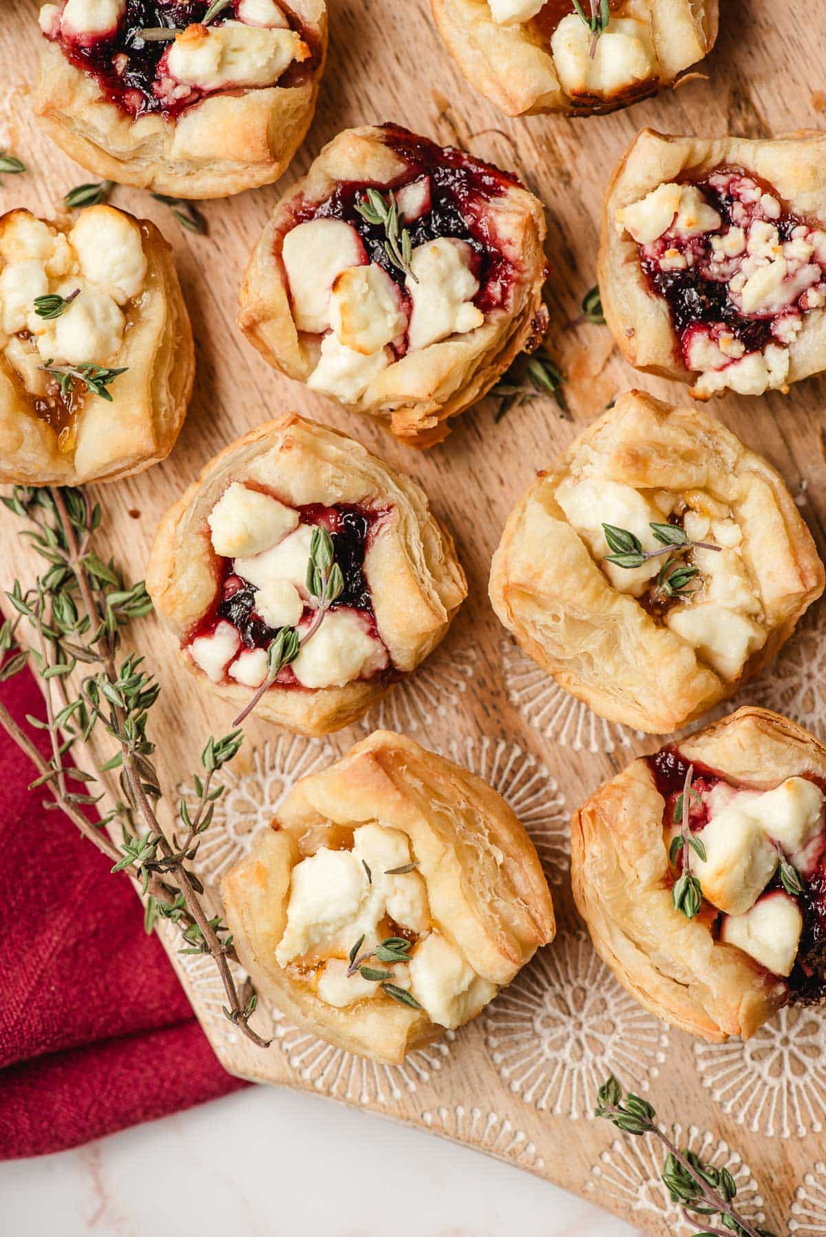 Decorative wooden board filled with goat cheese and puff pastry bites.