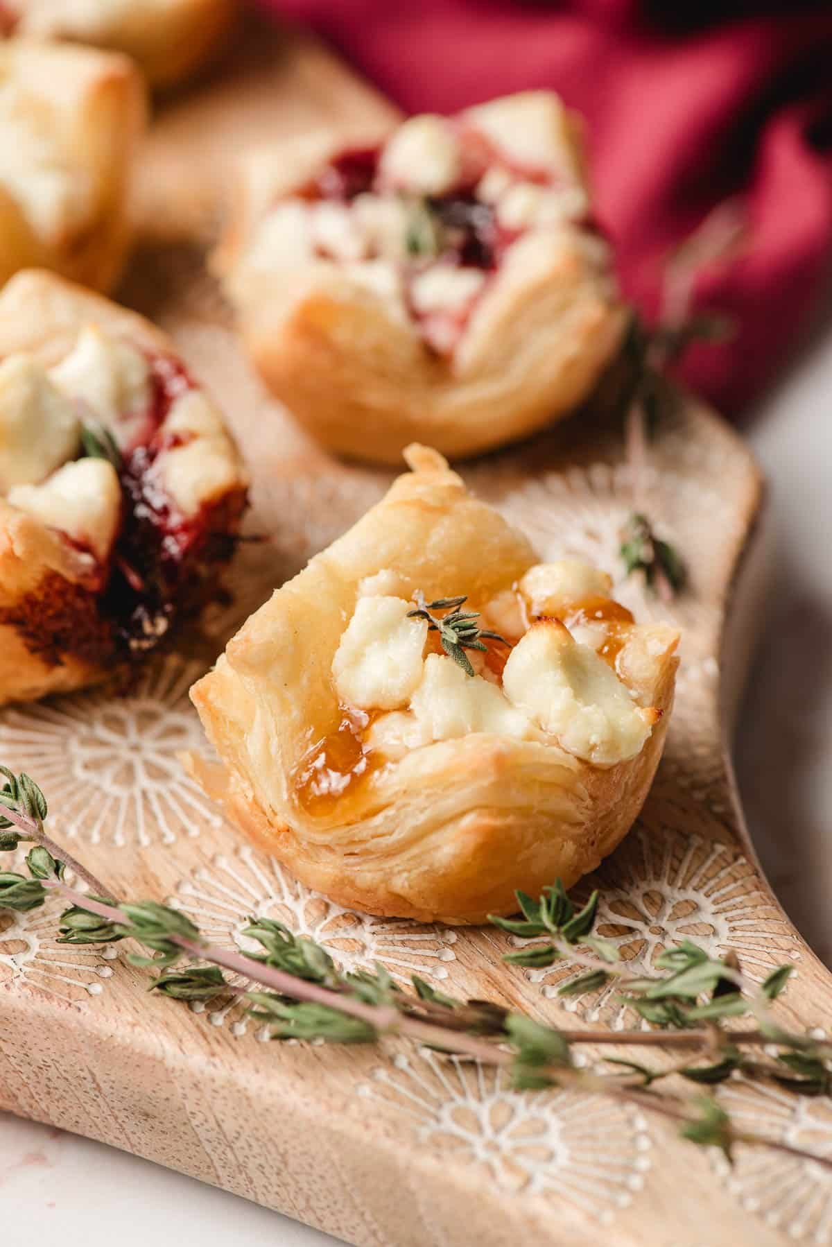 Goat cheese puff pastry bites on a wooden cutting board.