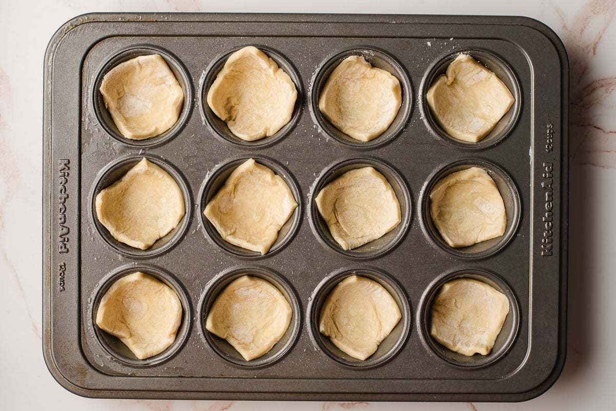 Puff pastry squares in a mini muffin tin.