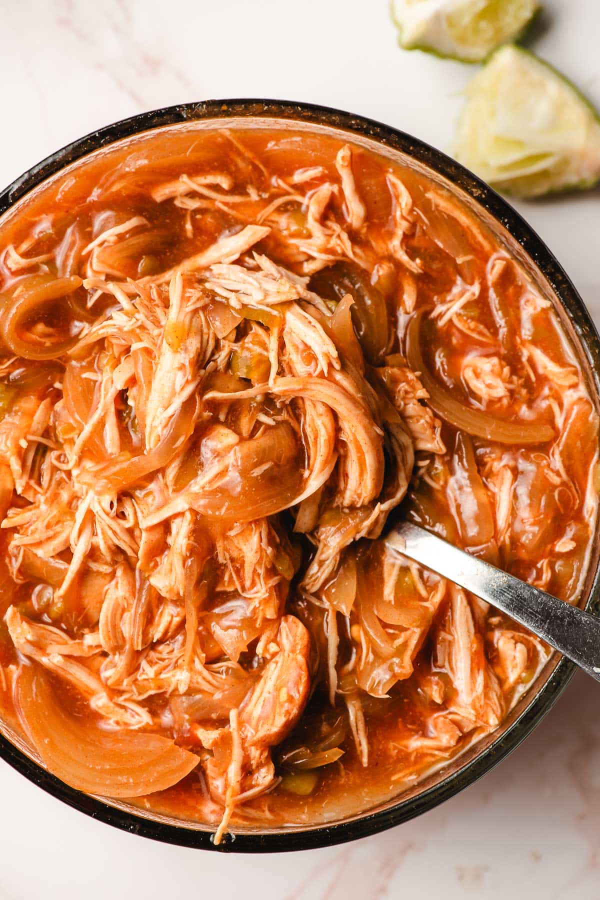 Shredded enchilada chicken in a glass bowl.