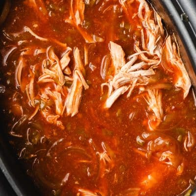 Shredded enchilada chicken in a crock pot.