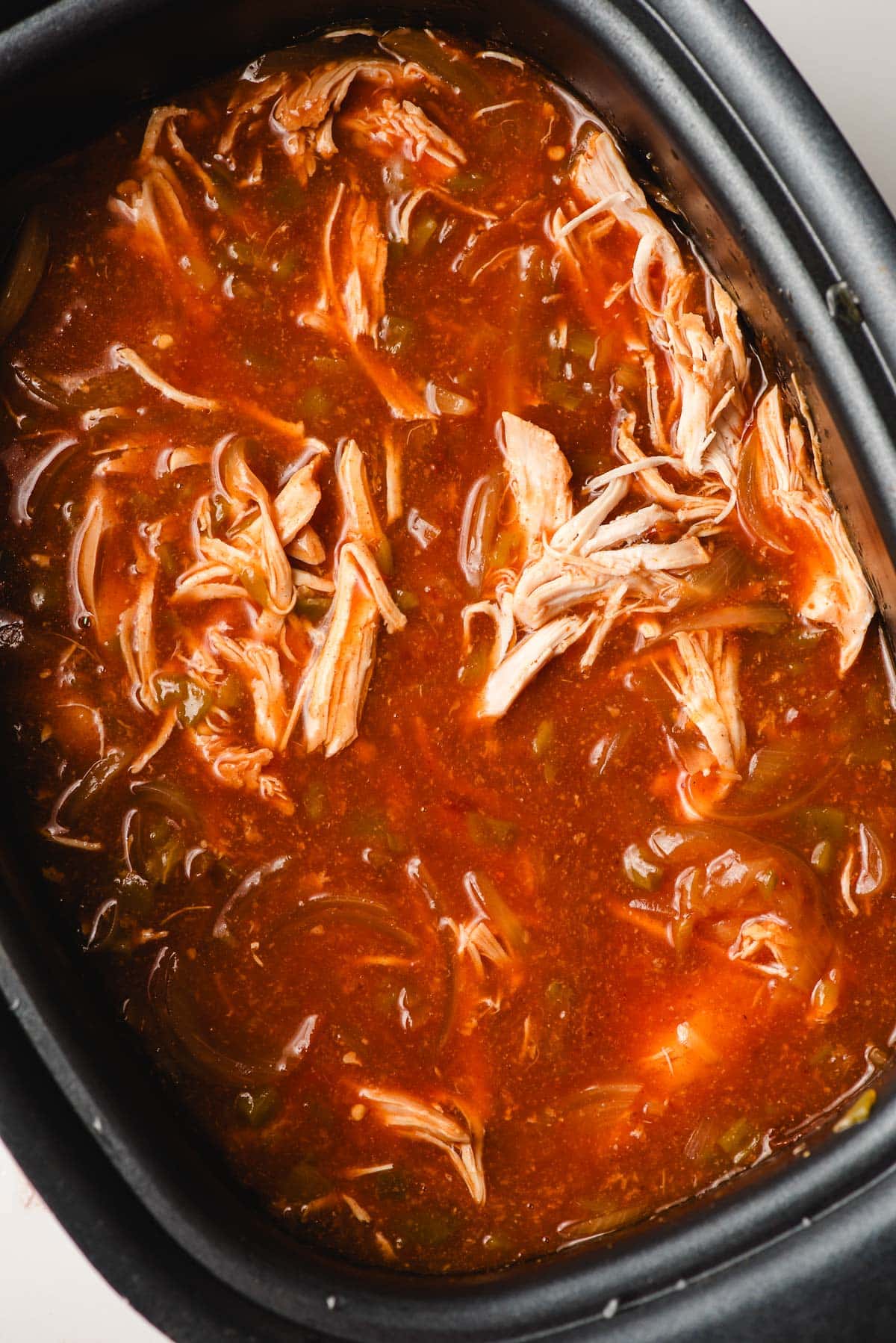 Shredded enchilada chicken in a crock pot.