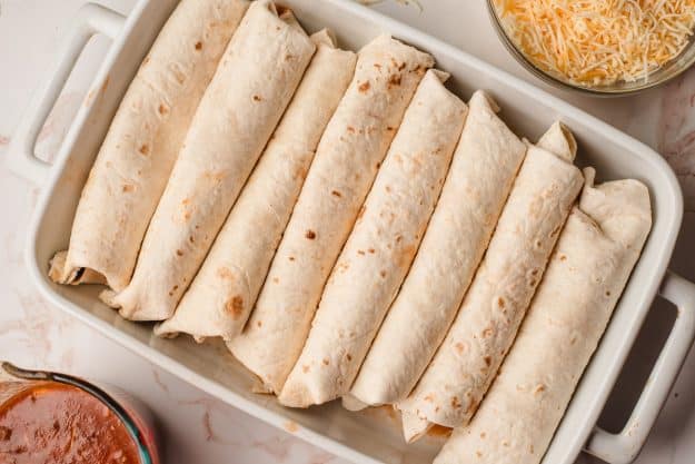 Freshly rolled enchiladas in a baking dish.