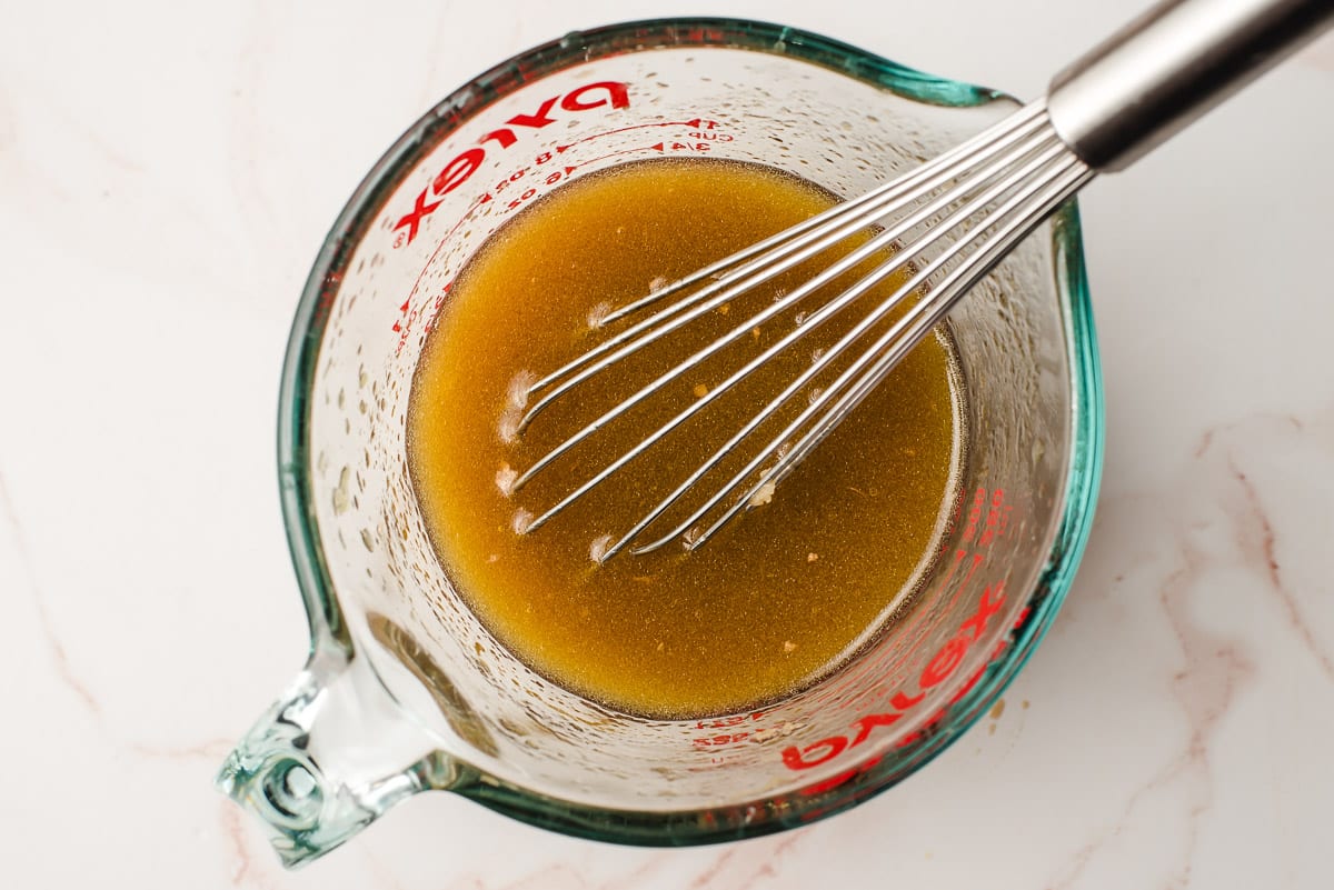 Whisked up orange vinaigrette in a glass measuring cup.