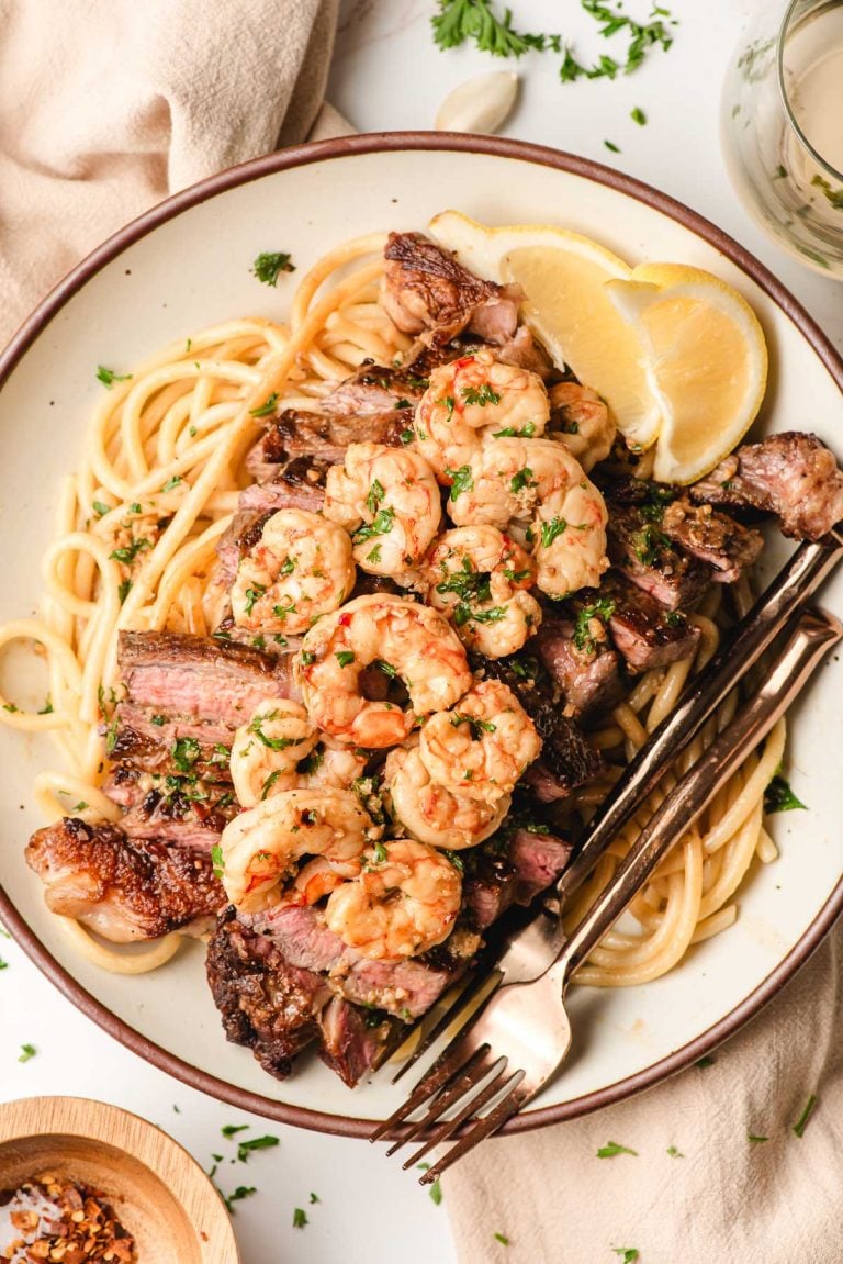 A plate of steak and shrimp scampi pasta.