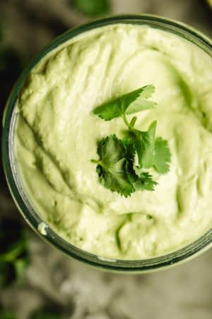 Avocado Lime Dressing in a mason jar with cilantro leaves on top.