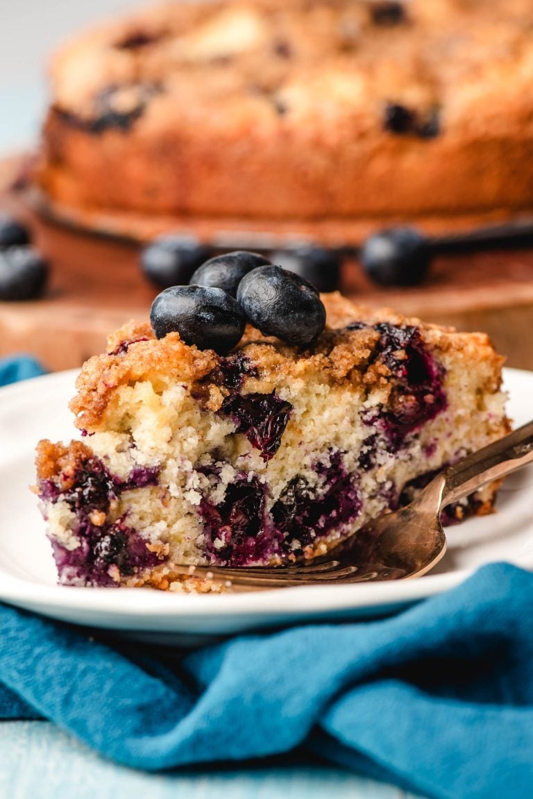 Slice of blueberry crumb coffee cake on a white plate.