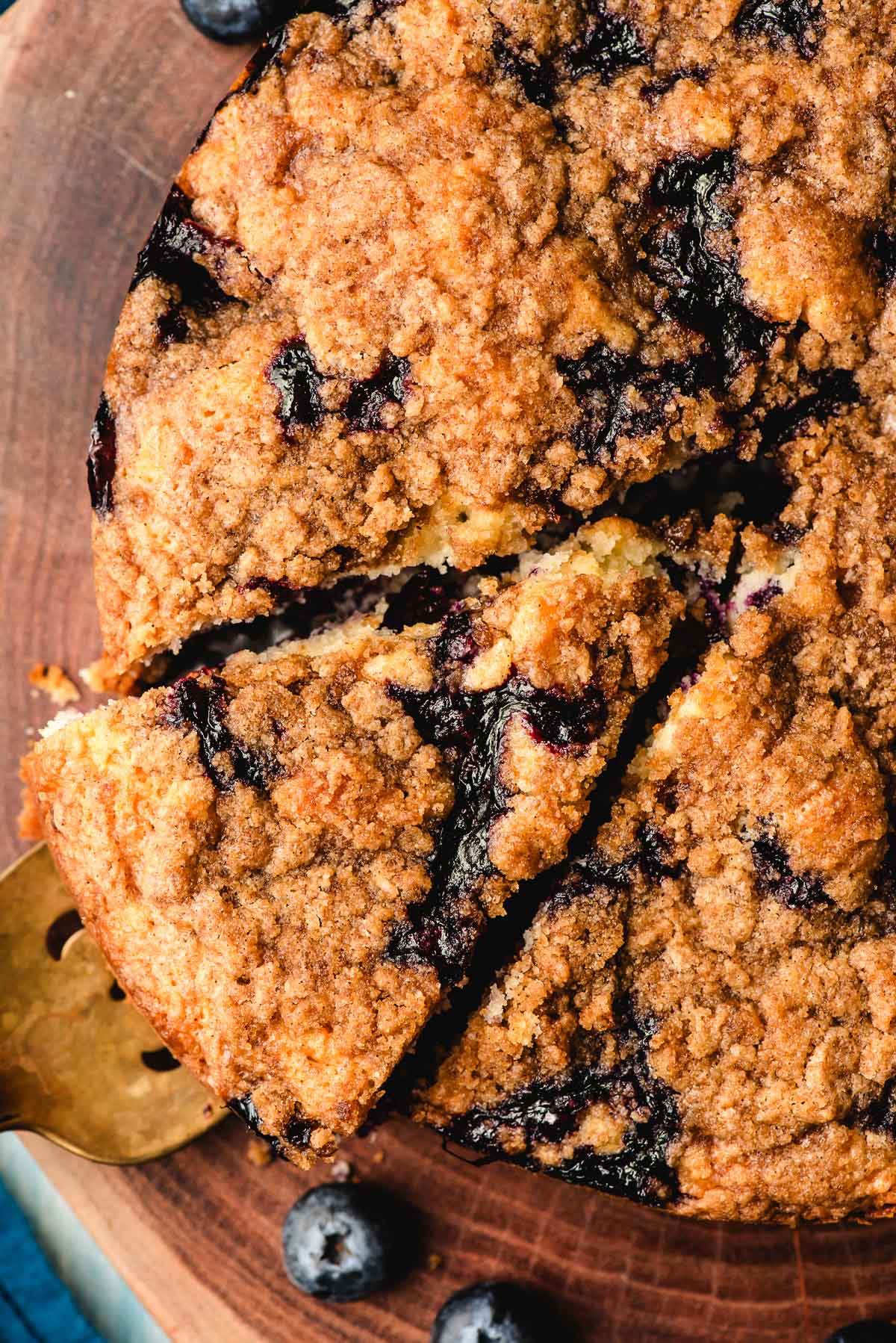 Slice of sour cream blueberry coffee cake on a wood platter.