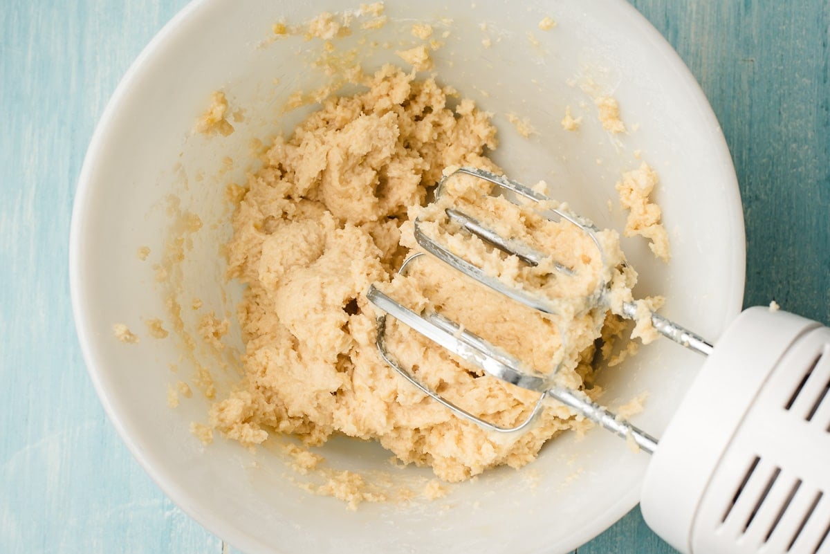 Sour cream, egg, and milk beaten into dry ingredients in a white bowl.