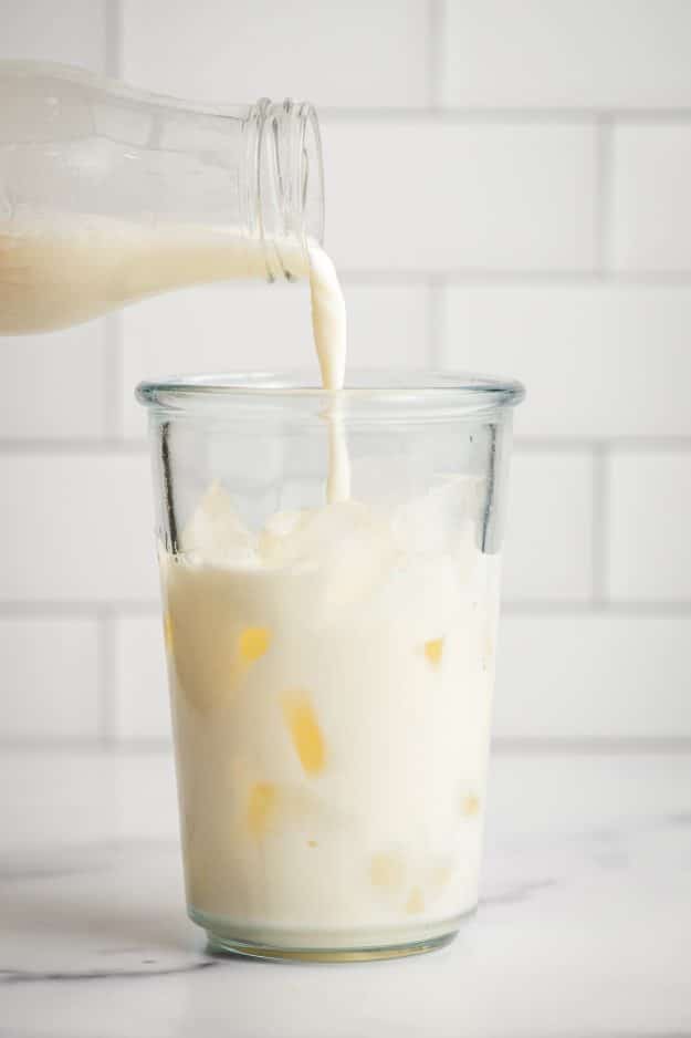 Cold milk poured over ice in a large glass.