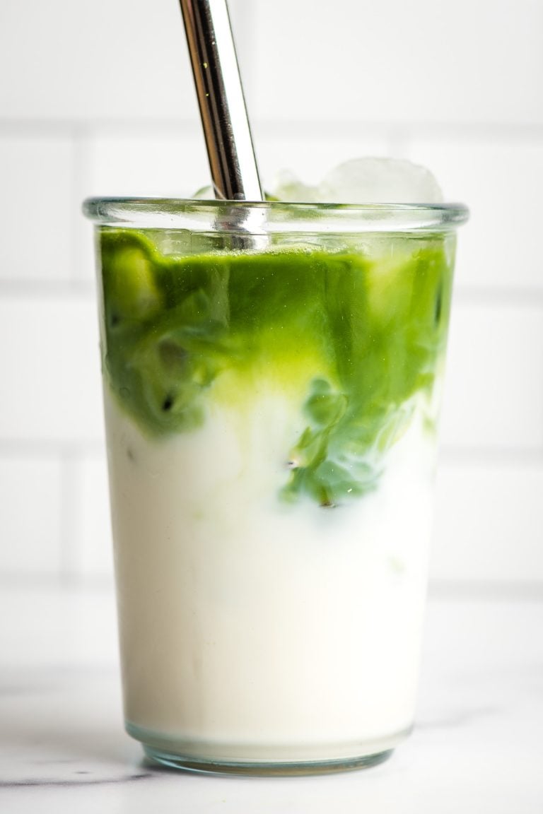 Matcha and water poured over ice and milk in a glass.