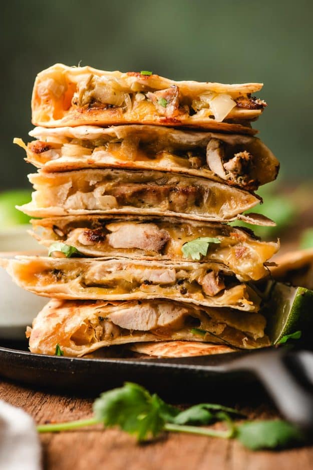 Cooked quesadillas stacked and ready to slice with melted cheese visible.