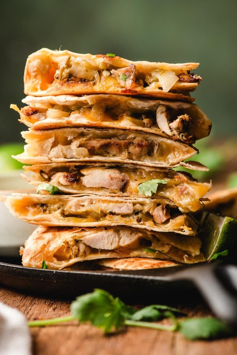 Cooked quesadillas stacked and ready to slice with melted cheese visible.