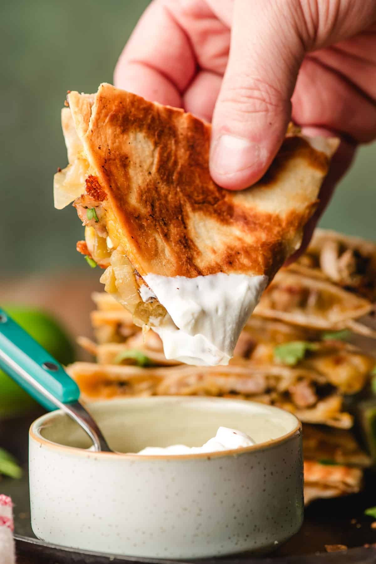 غمس شريحة الدجاج quesadilla جبني في الكريمة الحامضة.
