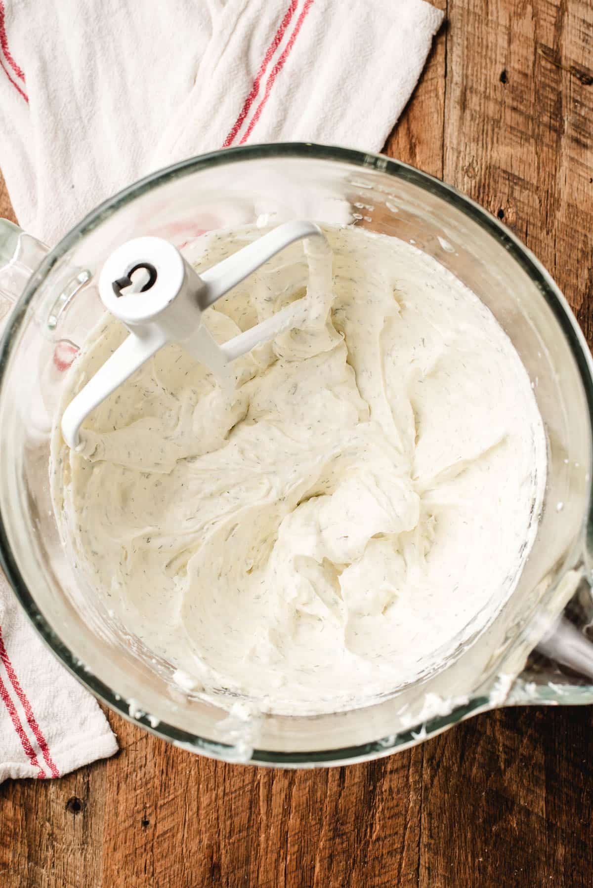 Mixing bowl with cream cheese and Greek yogurt being blended with herbs and seasonings.