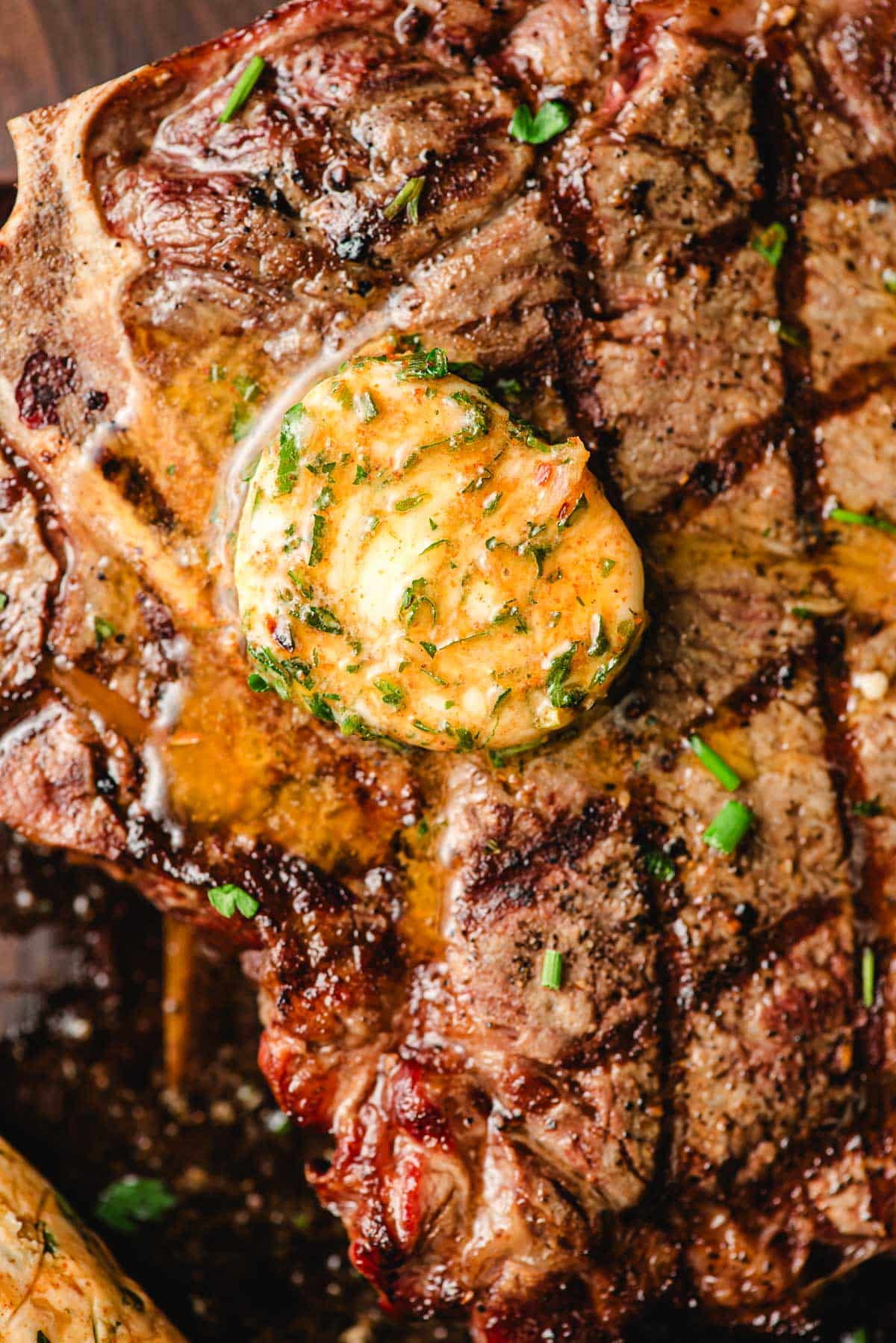 Pat of cowboy butter melting on a grilled t-bone steak.