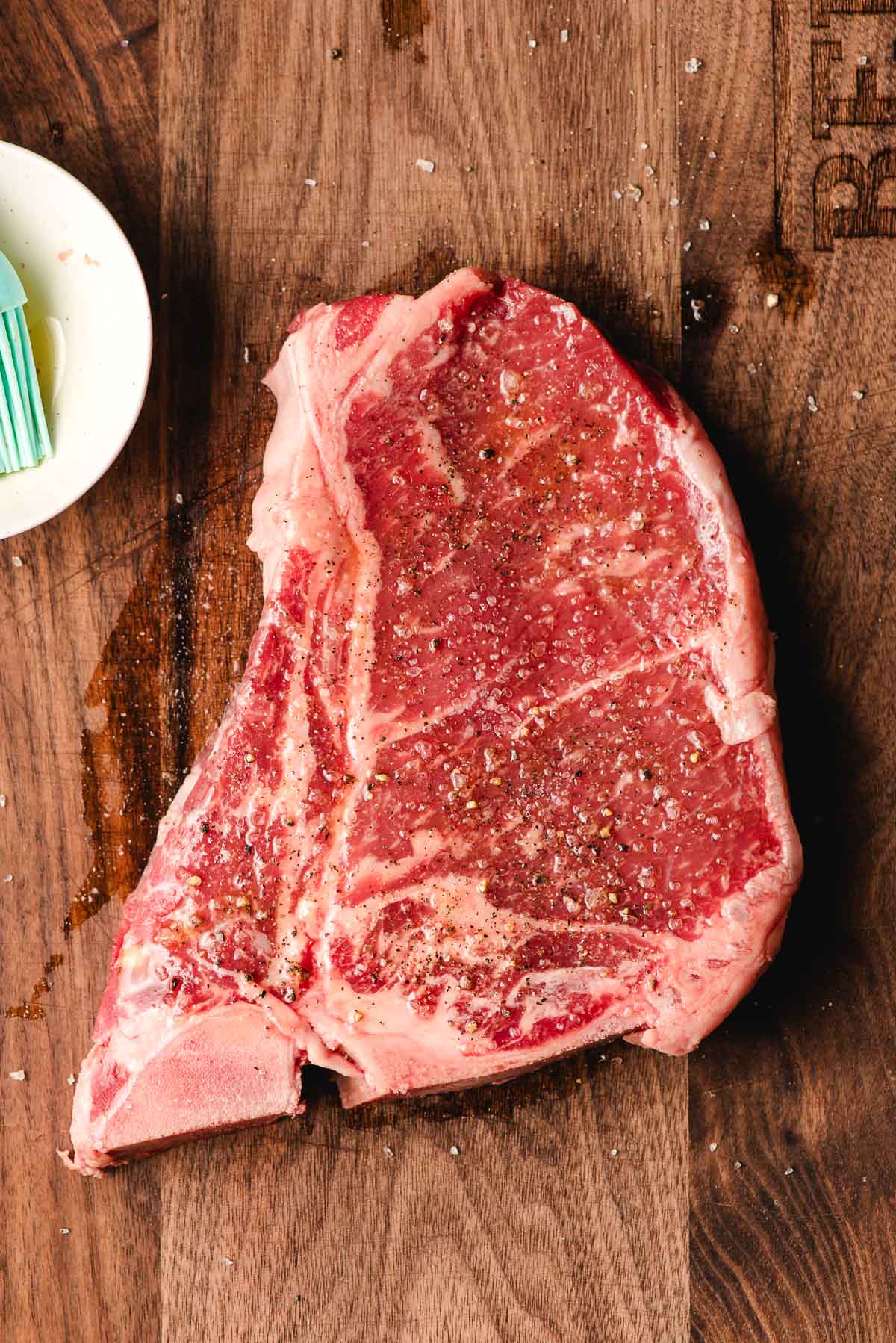 T bone steak brushed with olive oil and seasoned with salt and pepper.