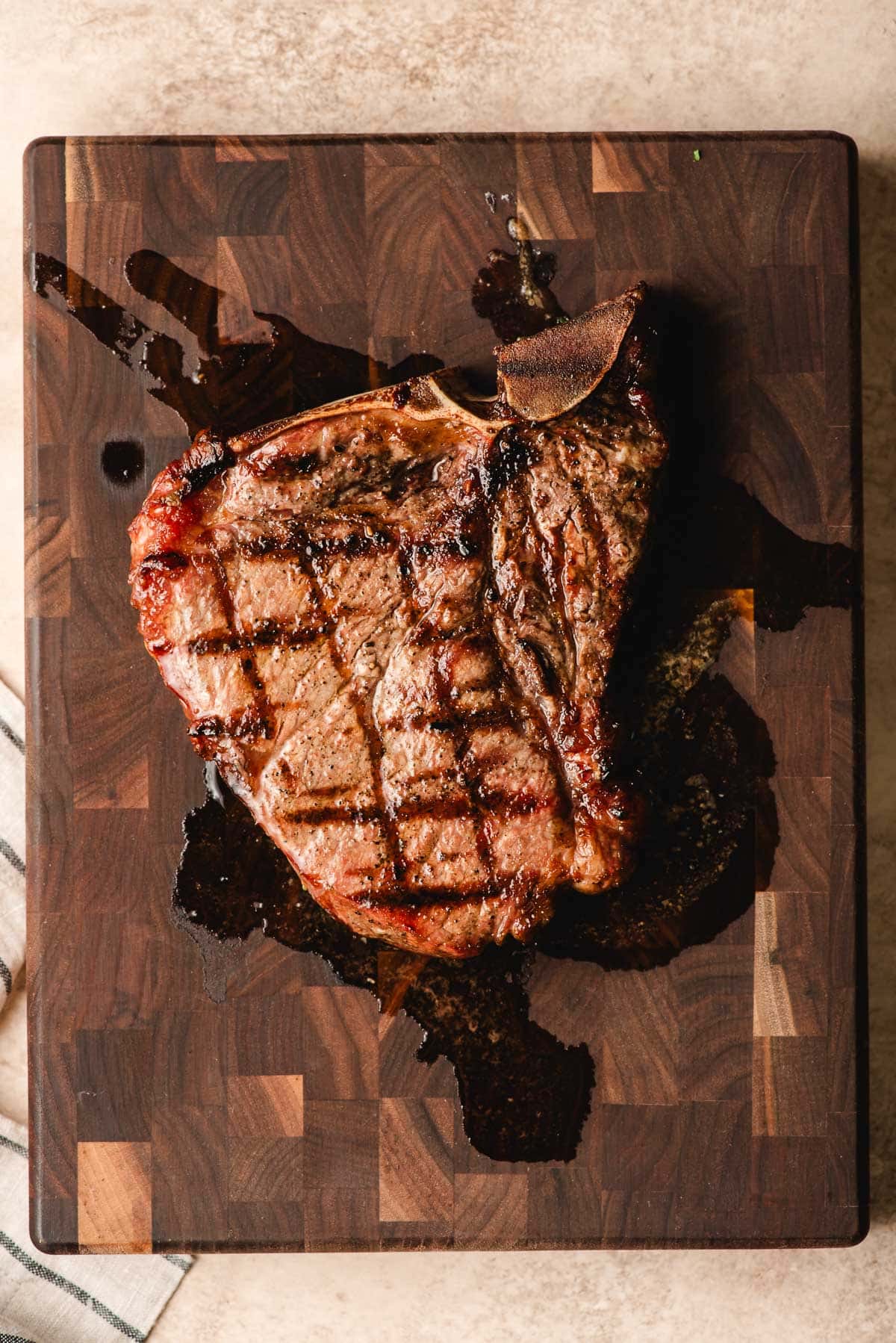 T-bone steak with grill marks on a wood cutting board.