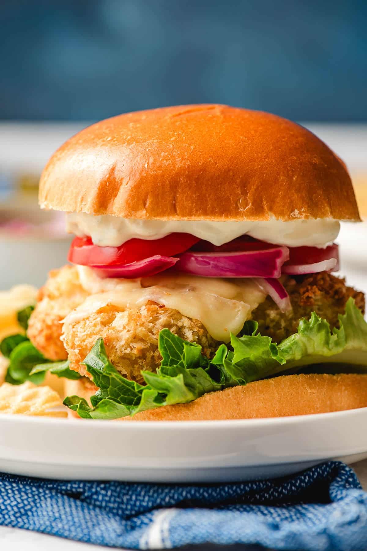  a cod fish sandwich layered with a bun, air fryer cod fillet, cheese, onion, and lettuce. 