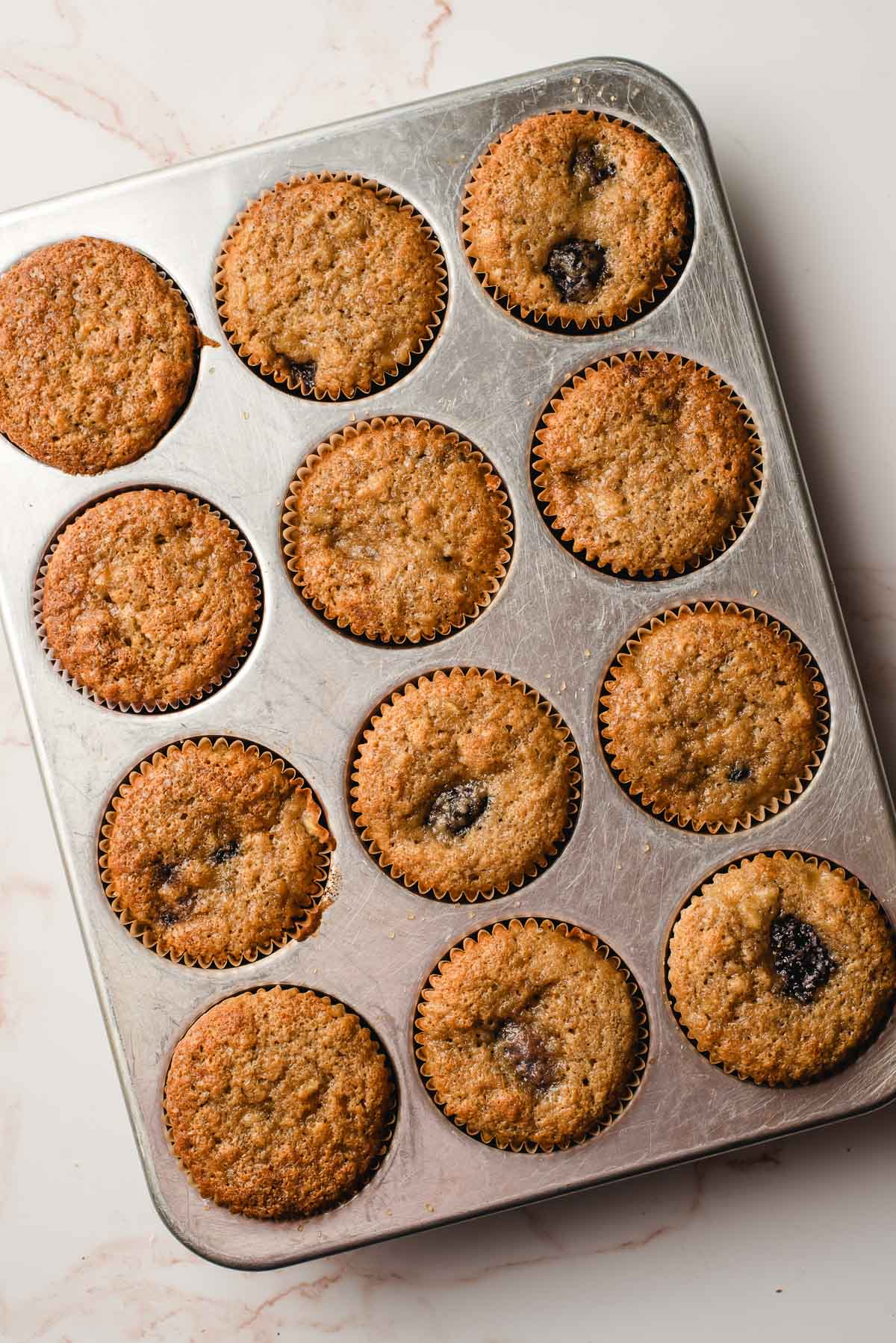 baked banana blackberry muffins cooling in a muffin tin