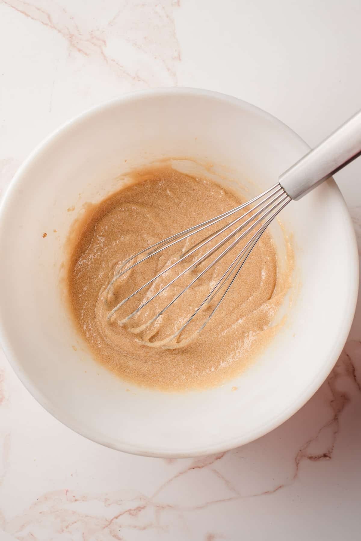butter and sugar mixed in a white bowl with a whisk