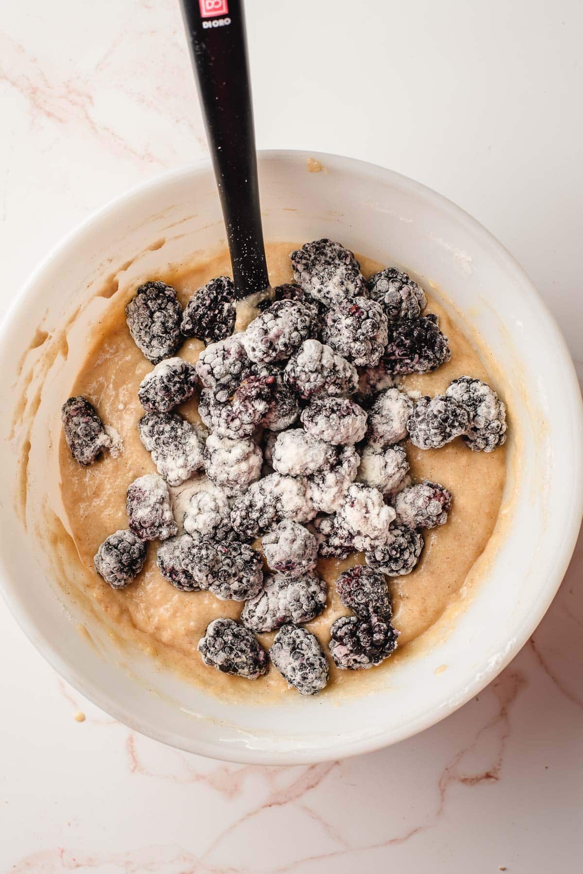 floured blackberries resting atop the banana blackberry muffin batter