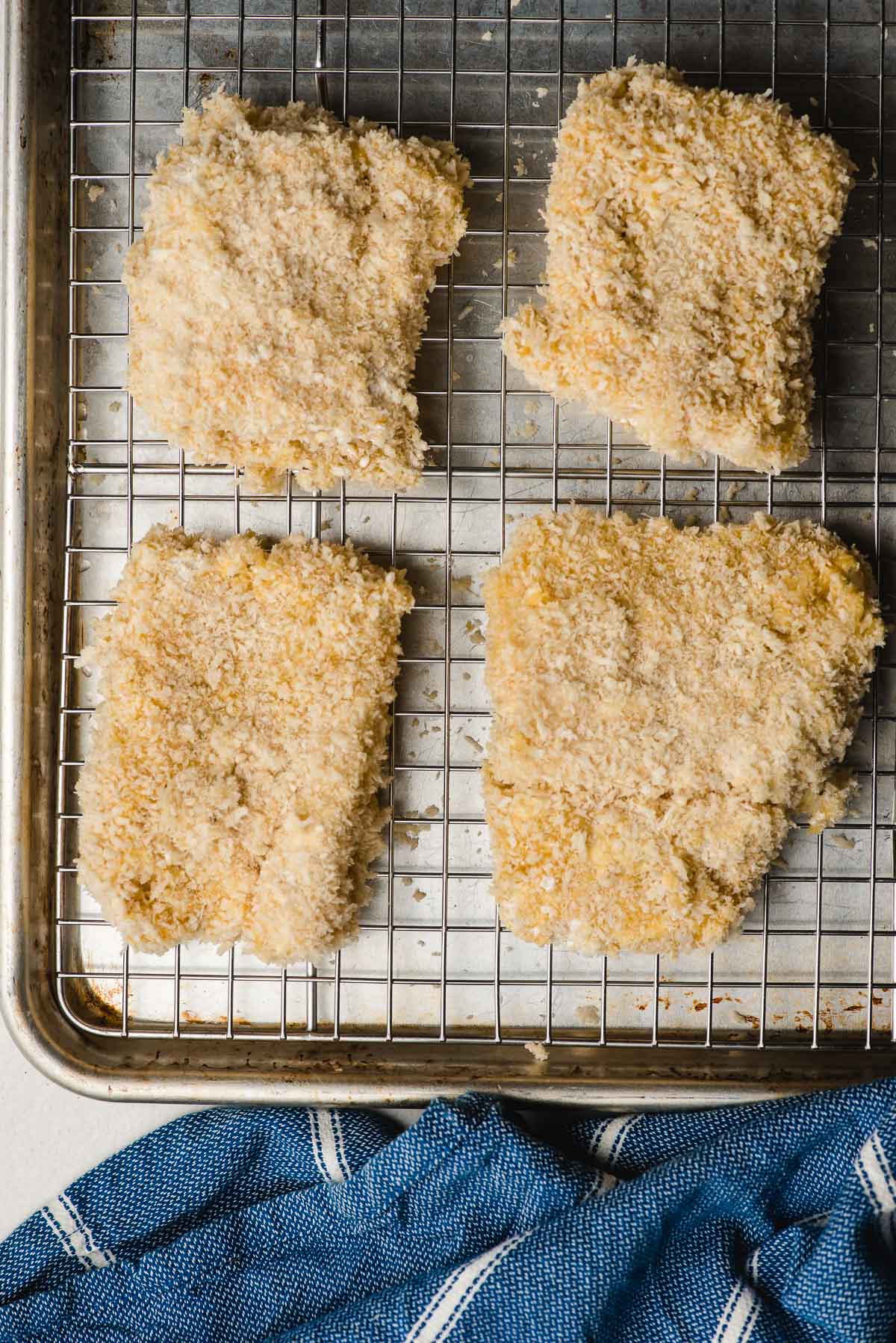 a sheet pan with a wire rack and breaded cod fillets resting atop waiting to be air fried 