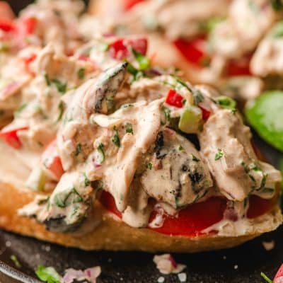Mexican chicken salad with bell peppers and onion, served open face on a slice of bread.