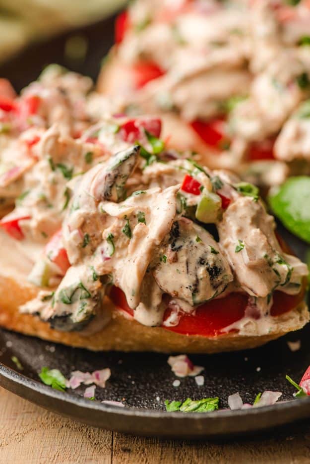 Mexican chicken salad with bell peppers and onion, served open face on a slice of bread.