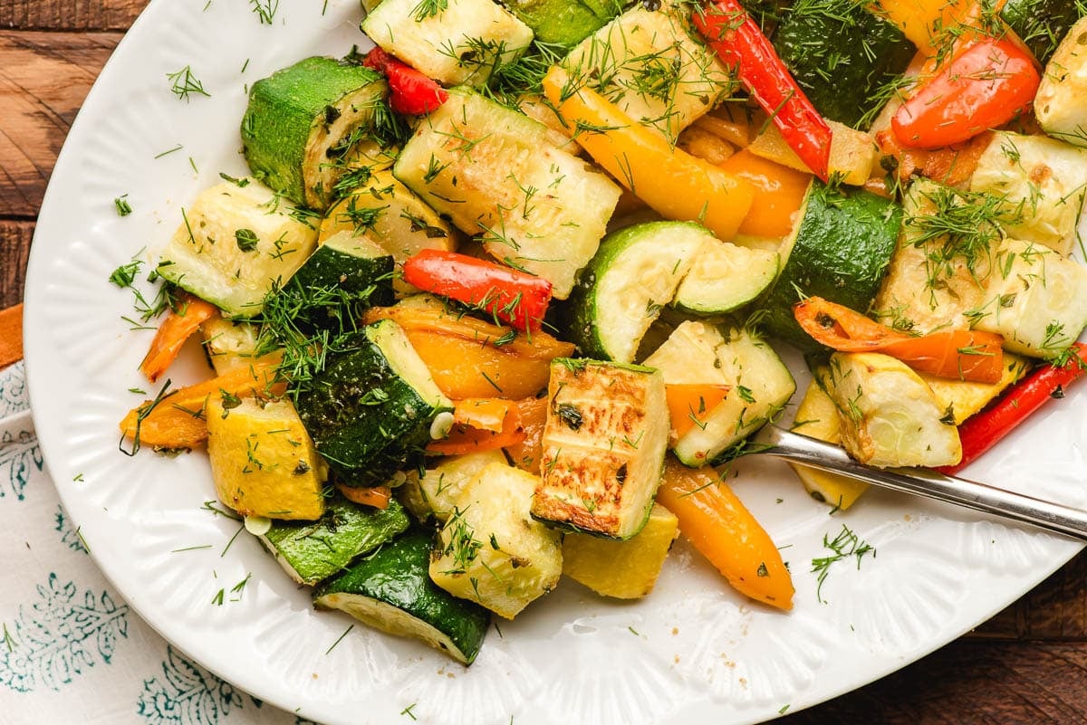 Baked zucchini and peppers with fresh dill on a serving dish.