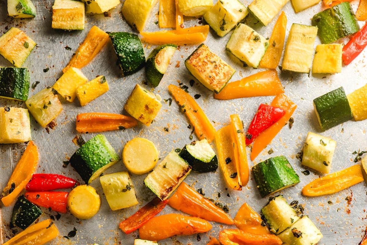 Zucchini, summer squash, and peppers on a baking sheet.