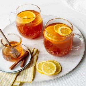 Tea Hot Toddies in two glass mugs with orange slices.