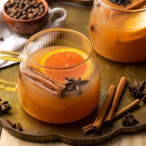 Mulled apple cider in a glass with an orange slice, cinnamon stick, and star anise.