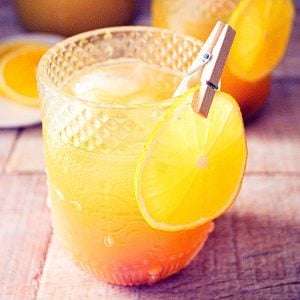 Fall Pumpkin Party Punch in a pretty glass with a slice of orange clipped to the side with a clothespin.