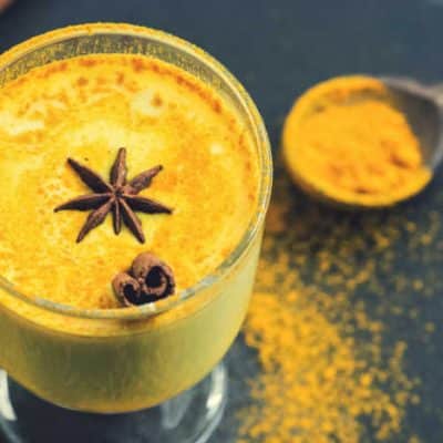 Golden milk in a glass with star anise and cinnamon.
