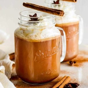 Hot Buttered Rum in a glass mug, topped with whipped cream and a cinnamon stick.