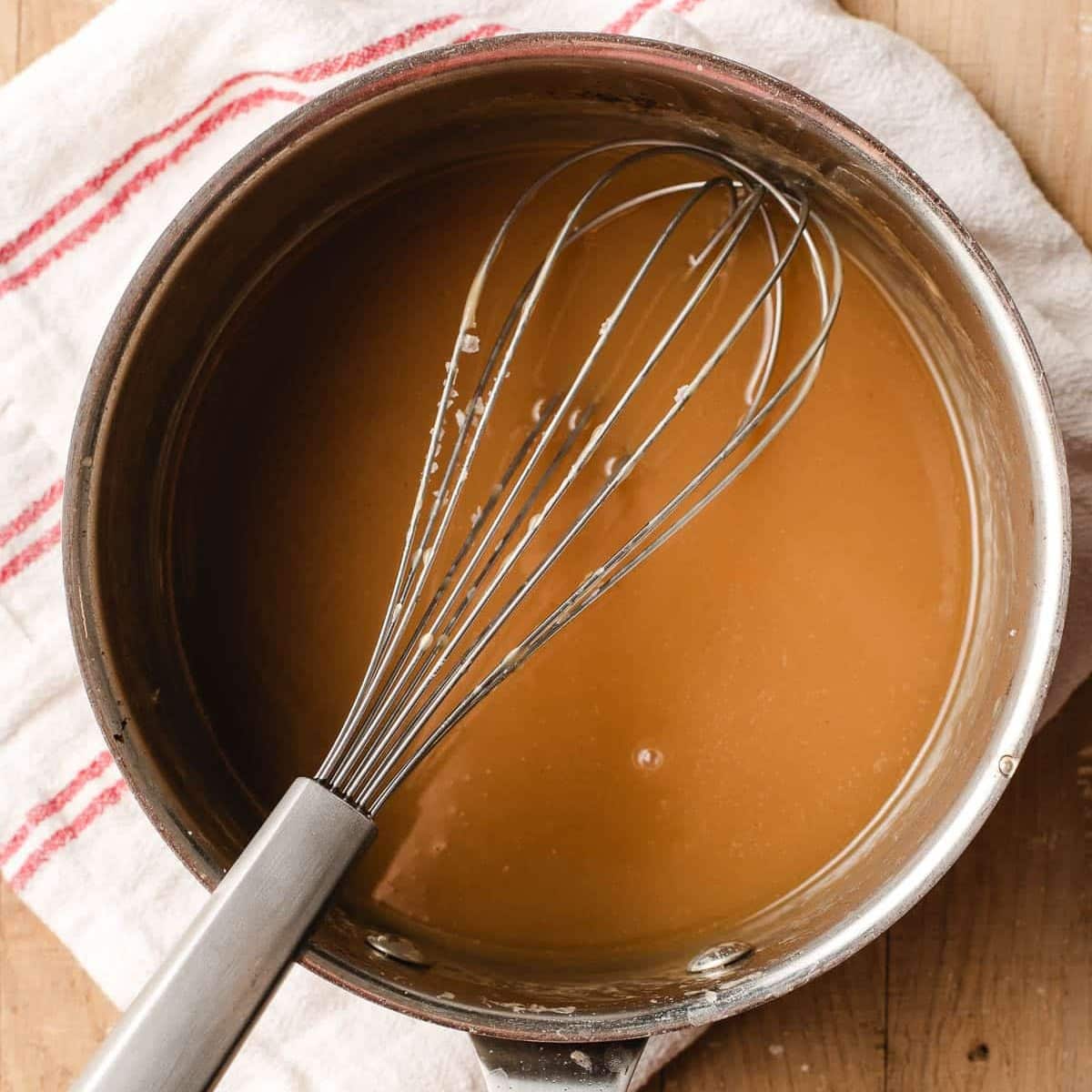Caramel with maple syrup in a sauce pan with a whisk.