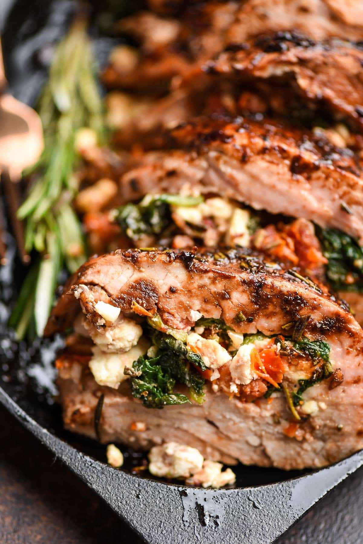 a close up photo of stuffed pork tenderloin stuffed with spinach, tomatoes, and cooked spinach.