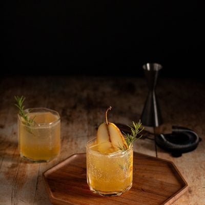 Pear Ginger Mocktails with half a pear and sprig of rosemary.
