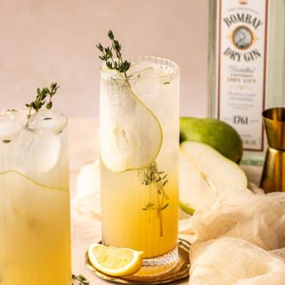 Two glasses of pear collins with fresh thyme leaves