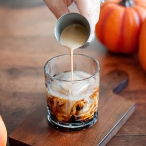 Pouring cream in a pumpkin white russian in a small glass.
