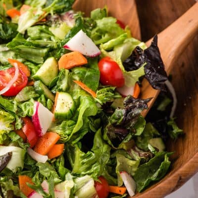 wooden bowl filled with a fresh garden salad with 2 wooden salad spoons