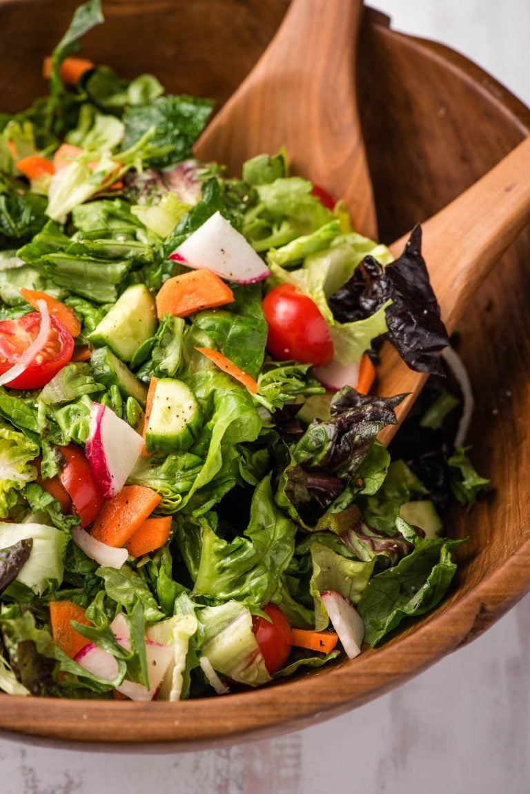 wooden bowl filled with a fresh garden salad with 2 wooden salad spoons