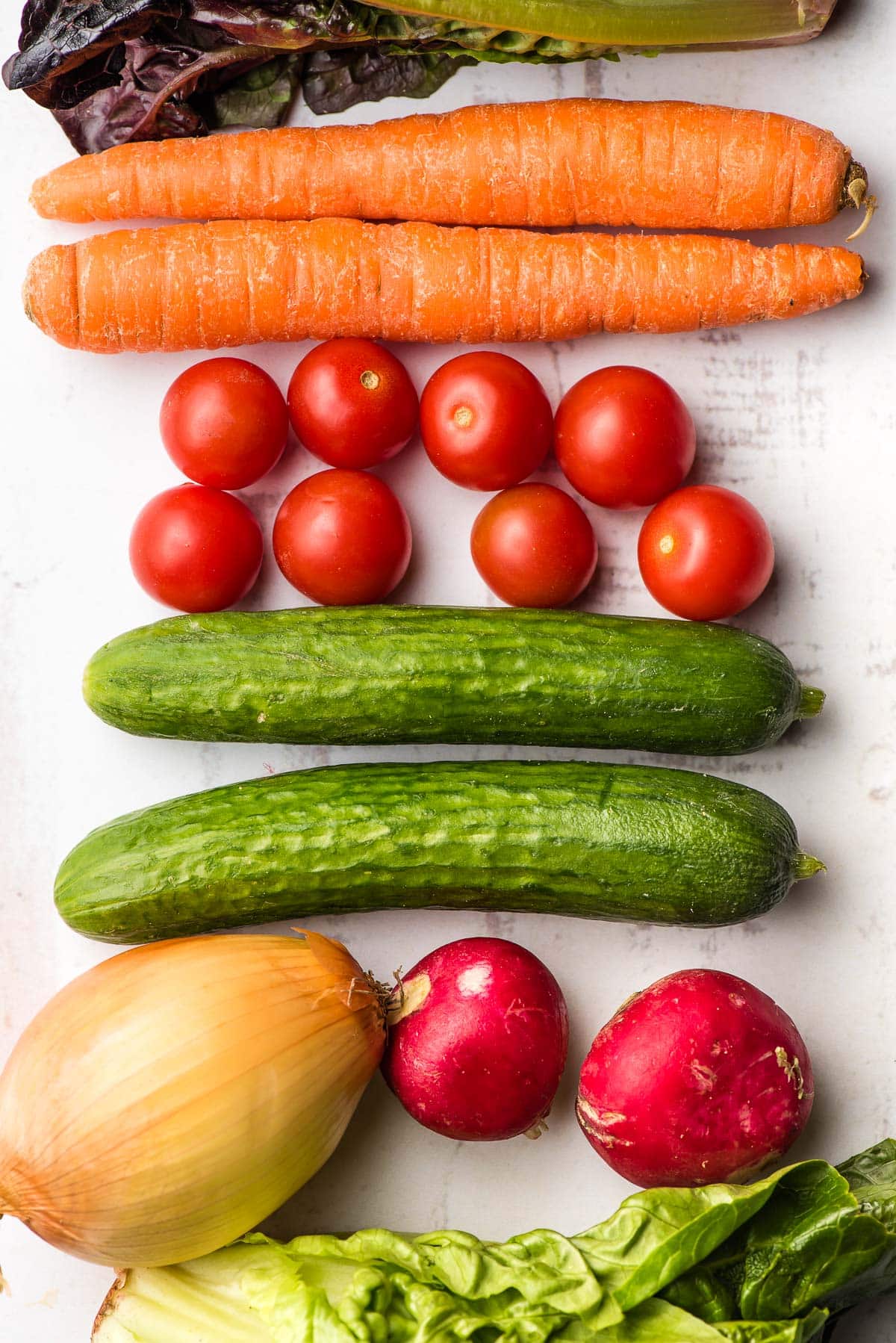 vegetables used in garden salad including carrots, tomatoes, cucumbers, radishes, and onion. 