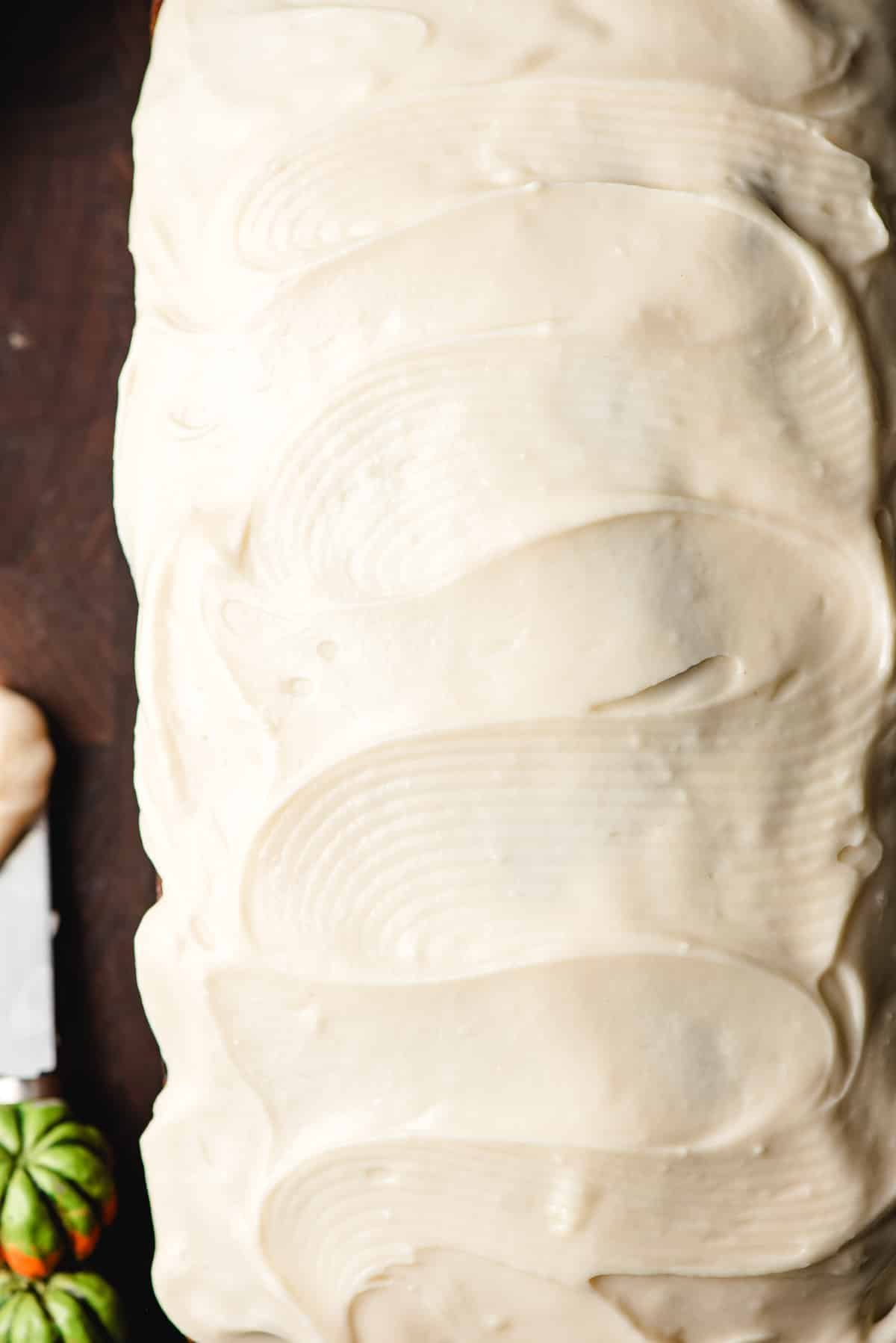 Cream cheese frosting spread on top of a loaf of pumpkin bread.