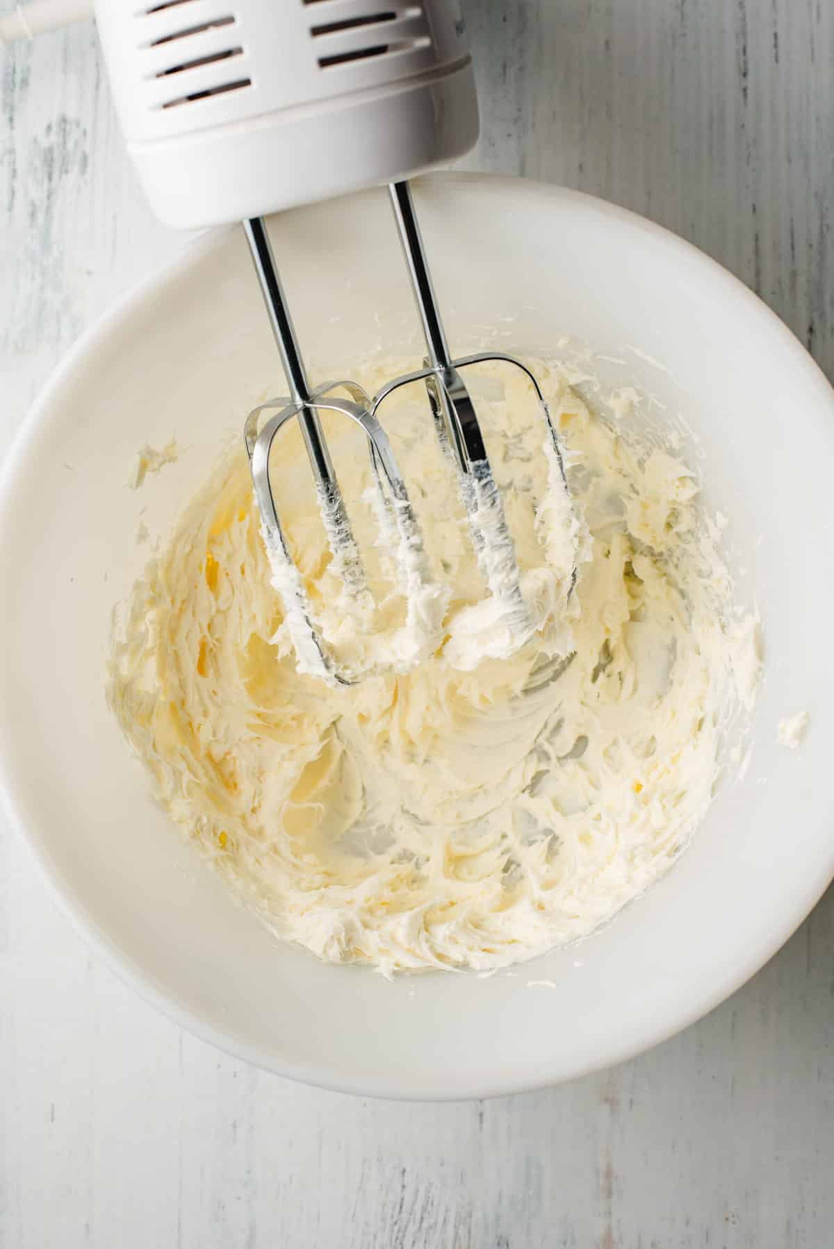 Cream cheese and butter beaten together in a white bowl.