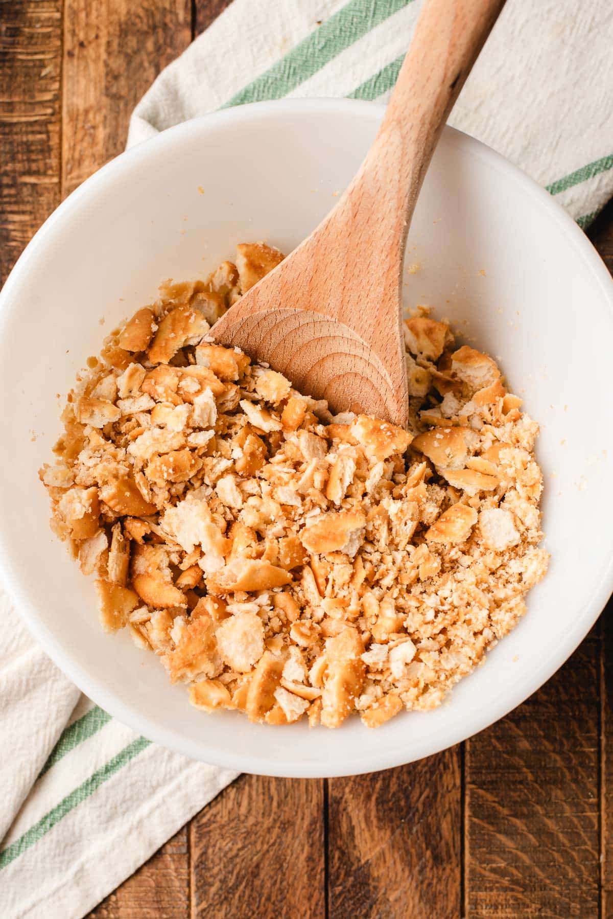 Ritz crackers crumbled and mixed with butter in a white bowl.
