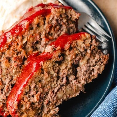 Two slices of stuffing meatloaf on a blue plate.