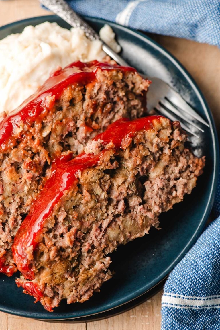 Two slices of stuffing meatloaf on a blue plate.